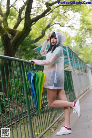 A woman walking down a path holding a colorful umbrella.