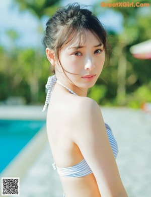 A woman in a blue and white bikini standing next to a pool.