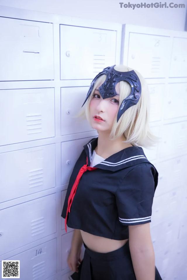 A woman in a school uniform standing in front of lockers.