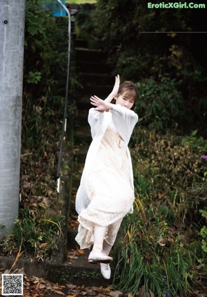 A woman leaning against a wall with her hand on her chin.