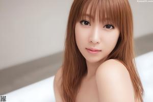 A woman in a white lingerie sitting on a white couch.