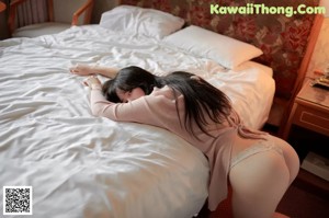 A woman sitting on a bed holding a camera.