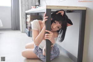 A woman sitting on a chair wearing a cat ears headband.
