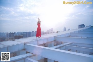 A woman in a red dress sitting on a ledge.