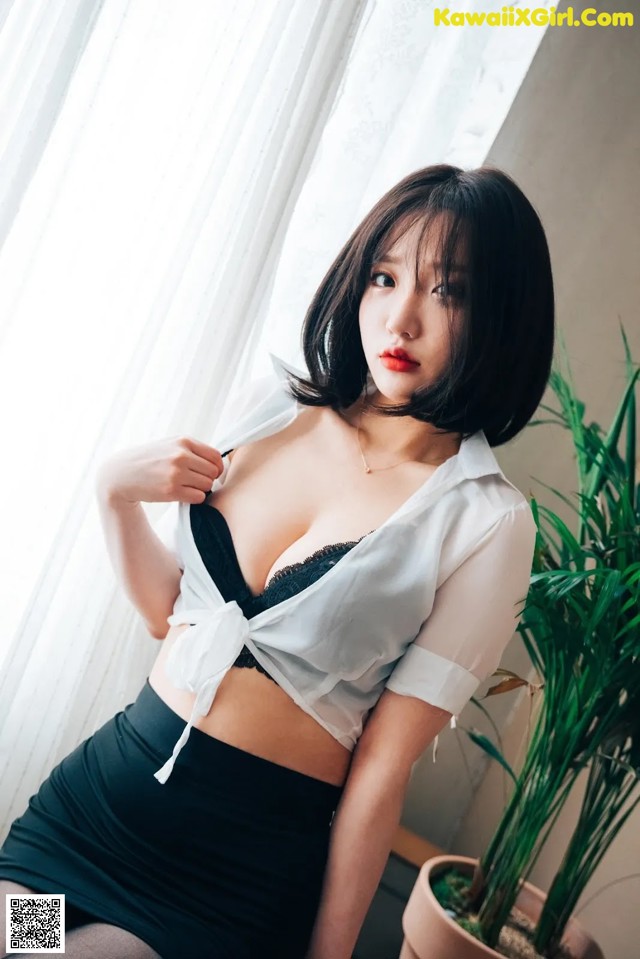 A woman in a white shirt and black skirt posing for a picture.