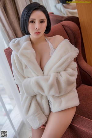 A woman in a white robe leaning against a window.