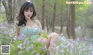A woman in a green dress standing in the woods.