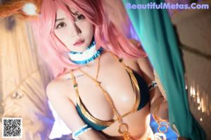 A woman with pink hair wearing a mask.
