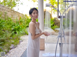 A woman in a white lingerie holding a shower head.