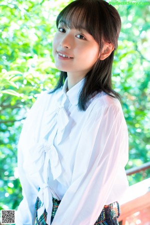 A woman in a white shirt and plaid skirt standing next to a radio.