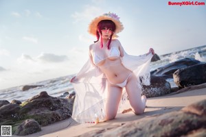 A woman with pink hair wearing a straw hat and sunglasses.