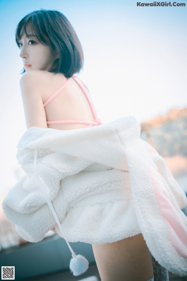 A woman in a pink bikini holding a white towel.