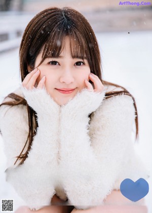 A woman in a white sweater and black skirt standing in the snow.