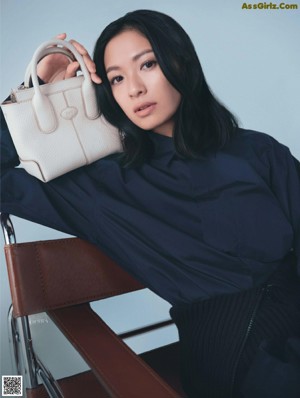 A woman in a black coat holding a red bag.