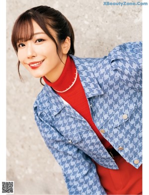 A woman leaning against a wall with her hand on her chin.