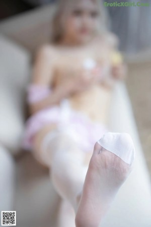 A woman in lingerie sitting on a couch eating a piece of food.