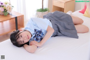 A woman in a blue shirt and gray skirt sitting on a couch.