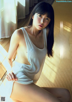 A woman in a white tank top is posing for a picture.