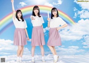 Two young women standing in front of a rainbow.