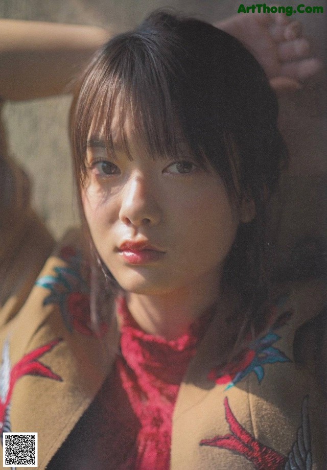 A woman in a brown jacket with a red scarf.