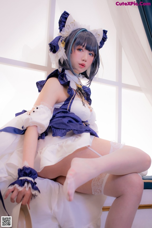 A woman in a maid outfit sitting on a chair.