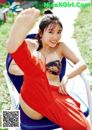 A woman in a red polka dot bikini posing on the beach.