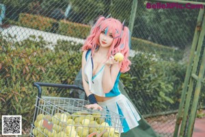 A woman with pink hair sitting on a tennis court.